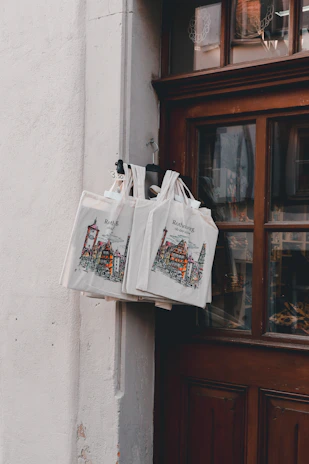 Branded tote bags with museum logos displayed in a bright retail setting.