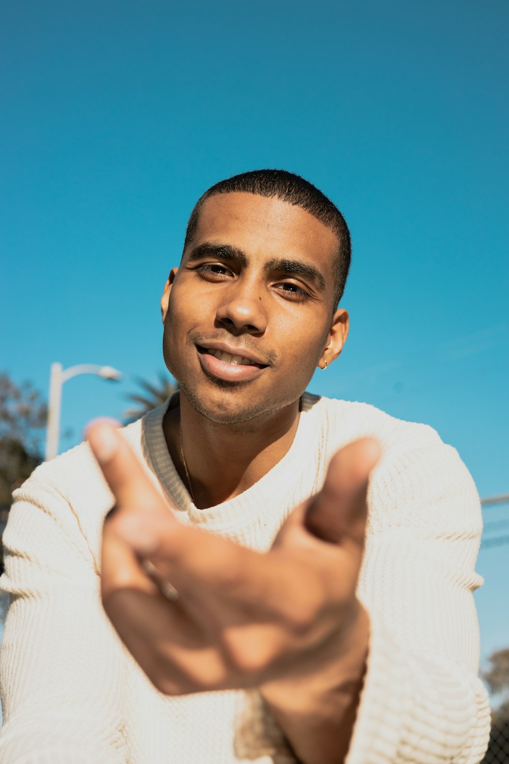 a man in a white sweater pointing at the camera