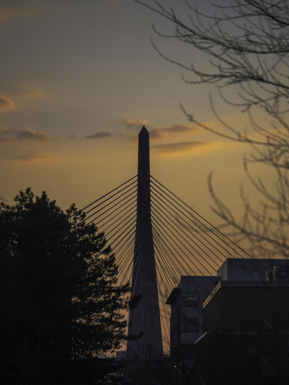 the sun is setting behind a tall bridge