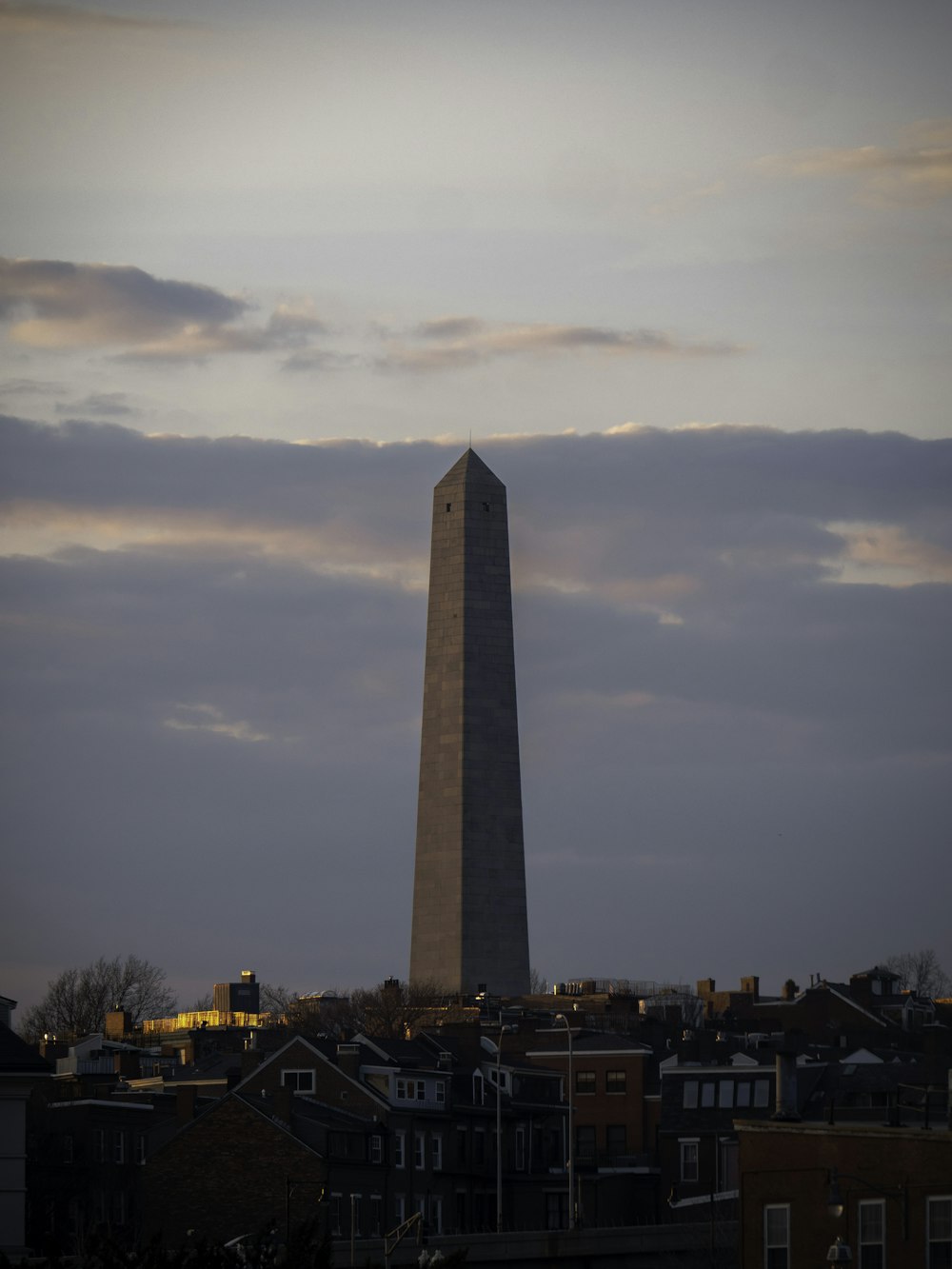 the washington monument is silhouetted against a cloudy sky