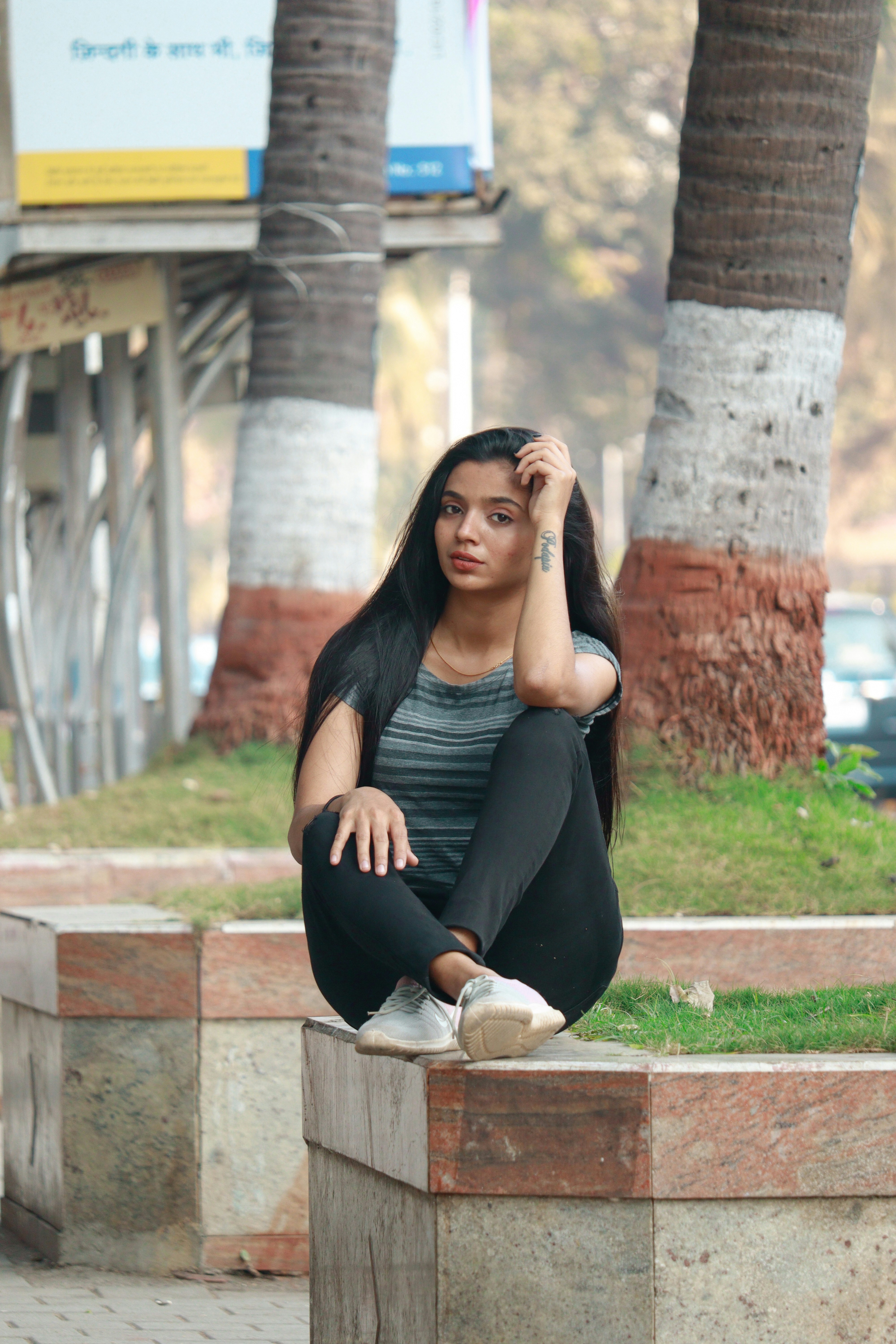 A woman sitting on a block in a park photo – Free Indian girl Image on ...