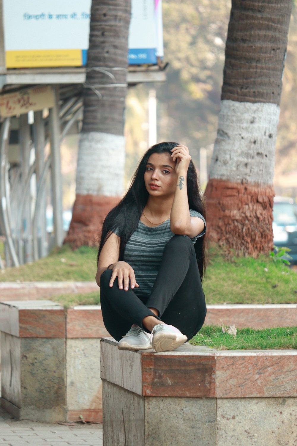 a woman sitting on a block in a park