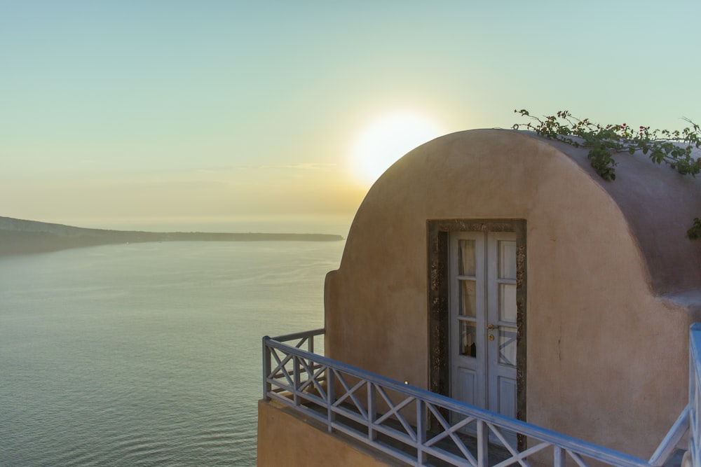 the sun is setting over the water behind a building