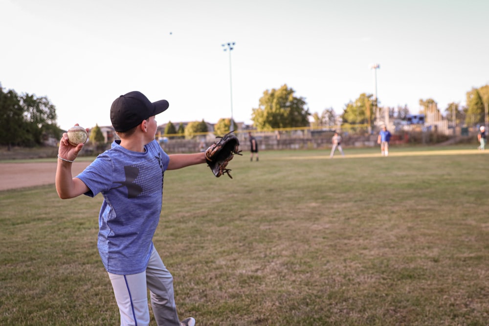 a young boy holding a catchers mitt on top of a field