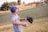 A smiling young baseball player holding a glove on a sunny field.