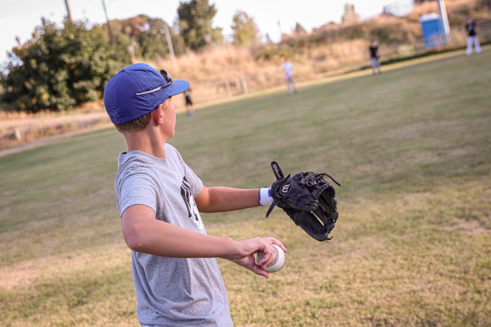 a young boy holding a baseball glove and ball
