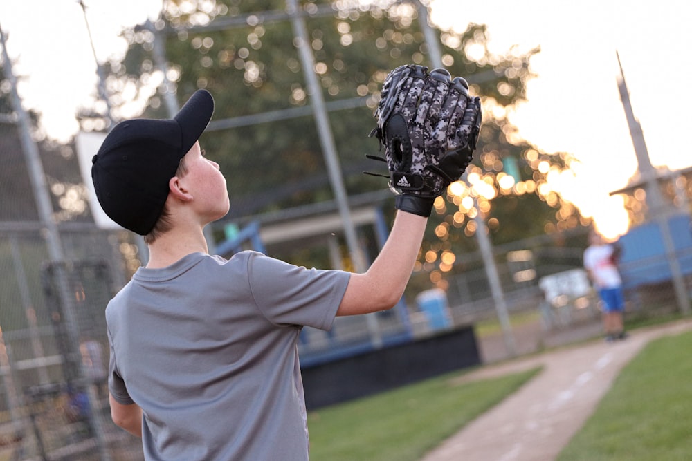 a young boy holding a catchers mitt on top of a field
