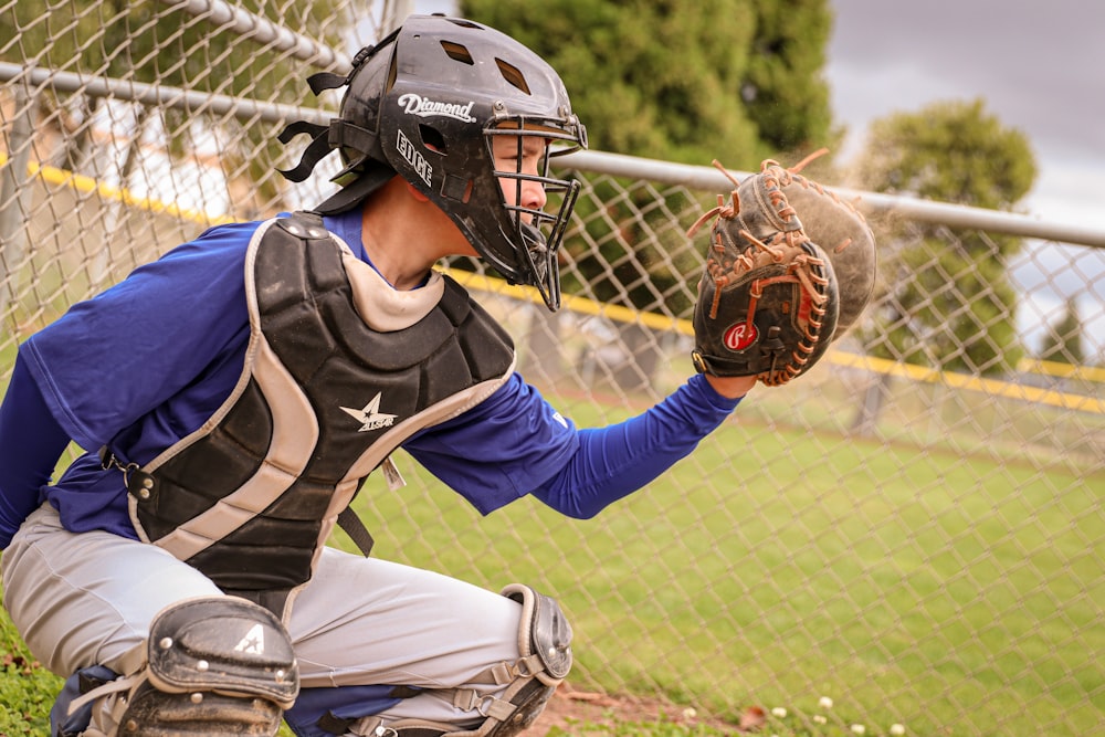 um jogador de beisebol ajoelhado segurando uma luva de catchers