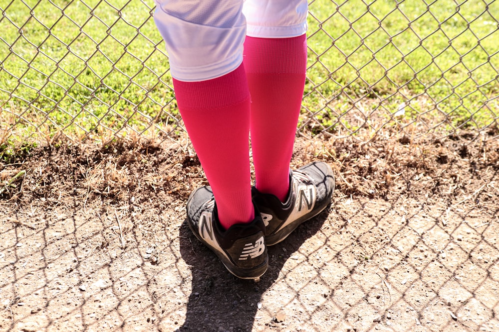 a person in a baseball uniform standing in front of a fence