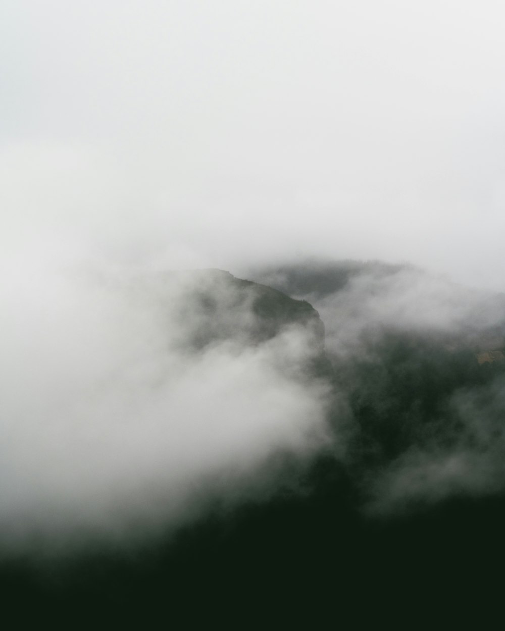 a mountain covered in fog and clouds on a cloudy day