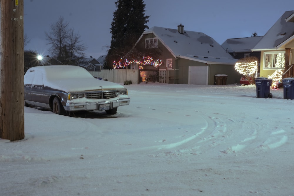 Un coche cubierto de nieve aparcado frente a una casa
