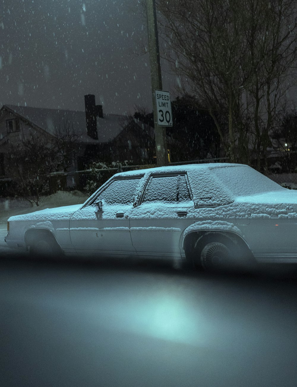 a white car is covered in snow at night
