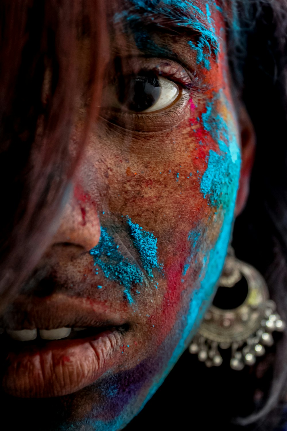 a close up of a woman with blue and red paint on her face