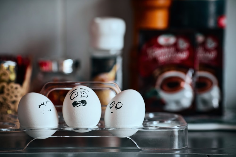 trois œufs avec des visages dessinés sur eux assis sur un comptoir