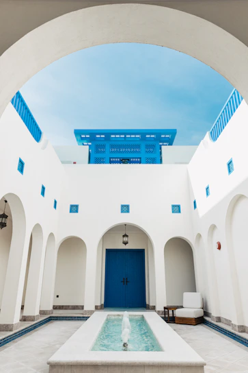 a white building with a blue door and a fountain