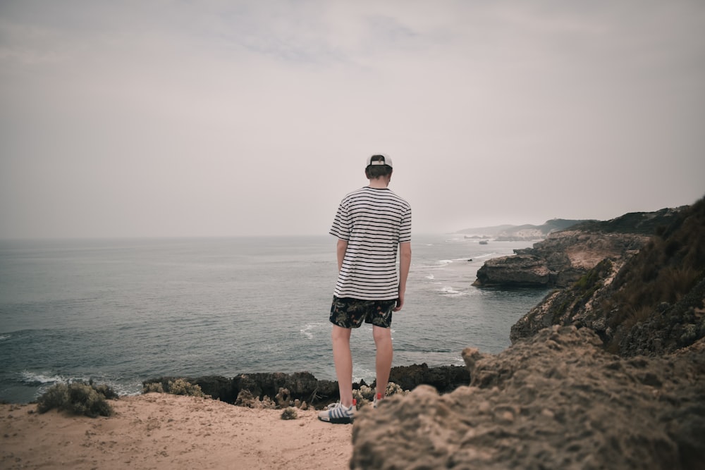 Ein Mann steht auf einer Klippe mit Blick auf den Ozean