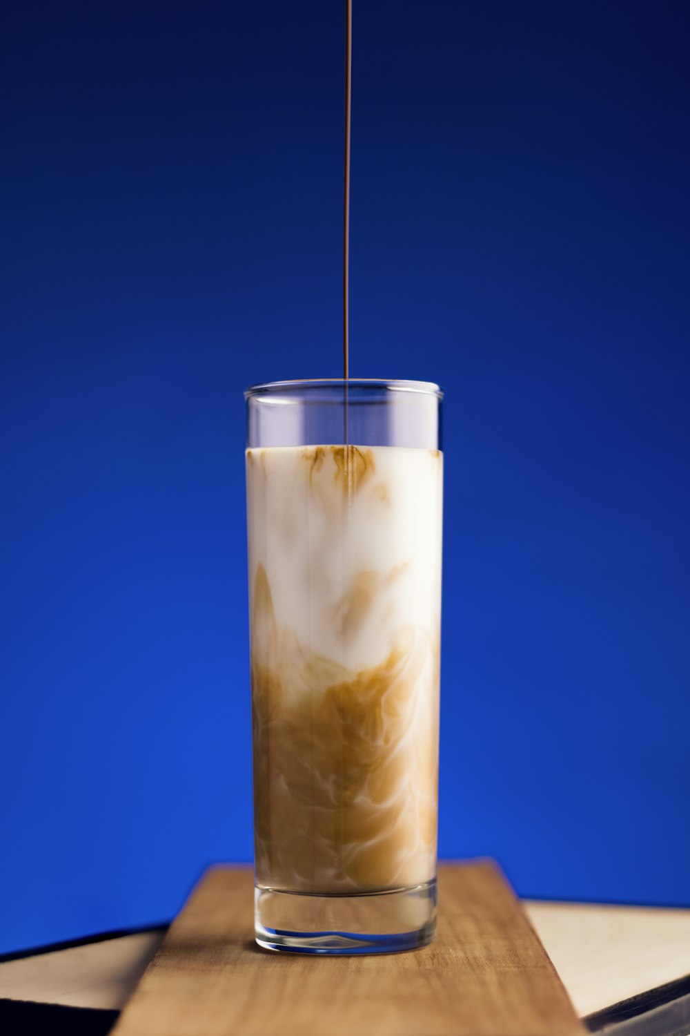 a glass filled with liquid sitting on top of a wooden table