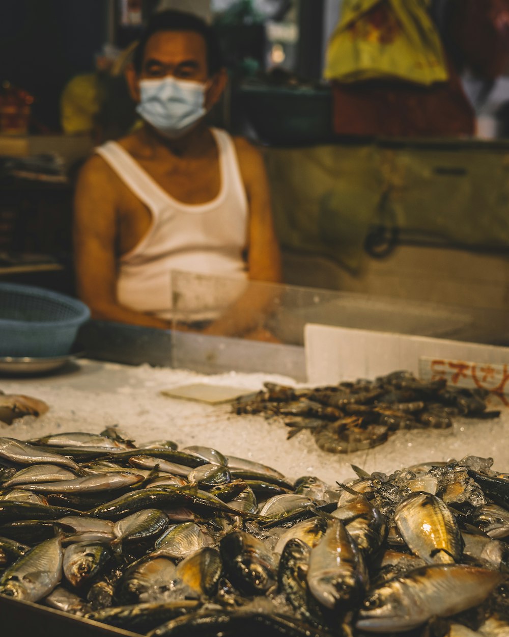 a woman wearing a face mask in front of a fish market