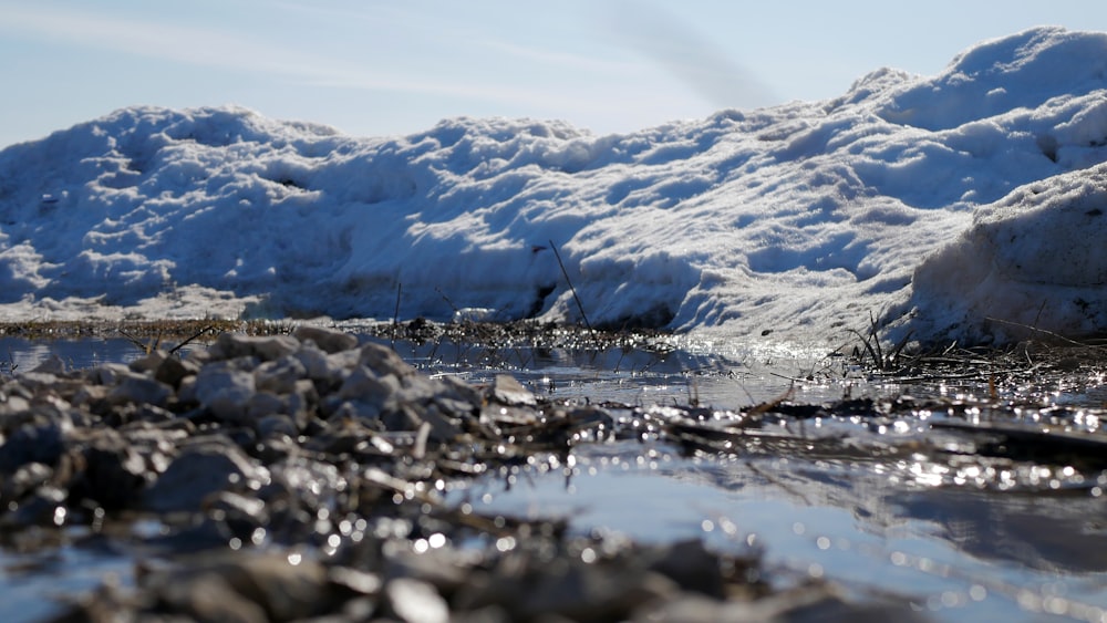 a small stream of water surrounded by snow