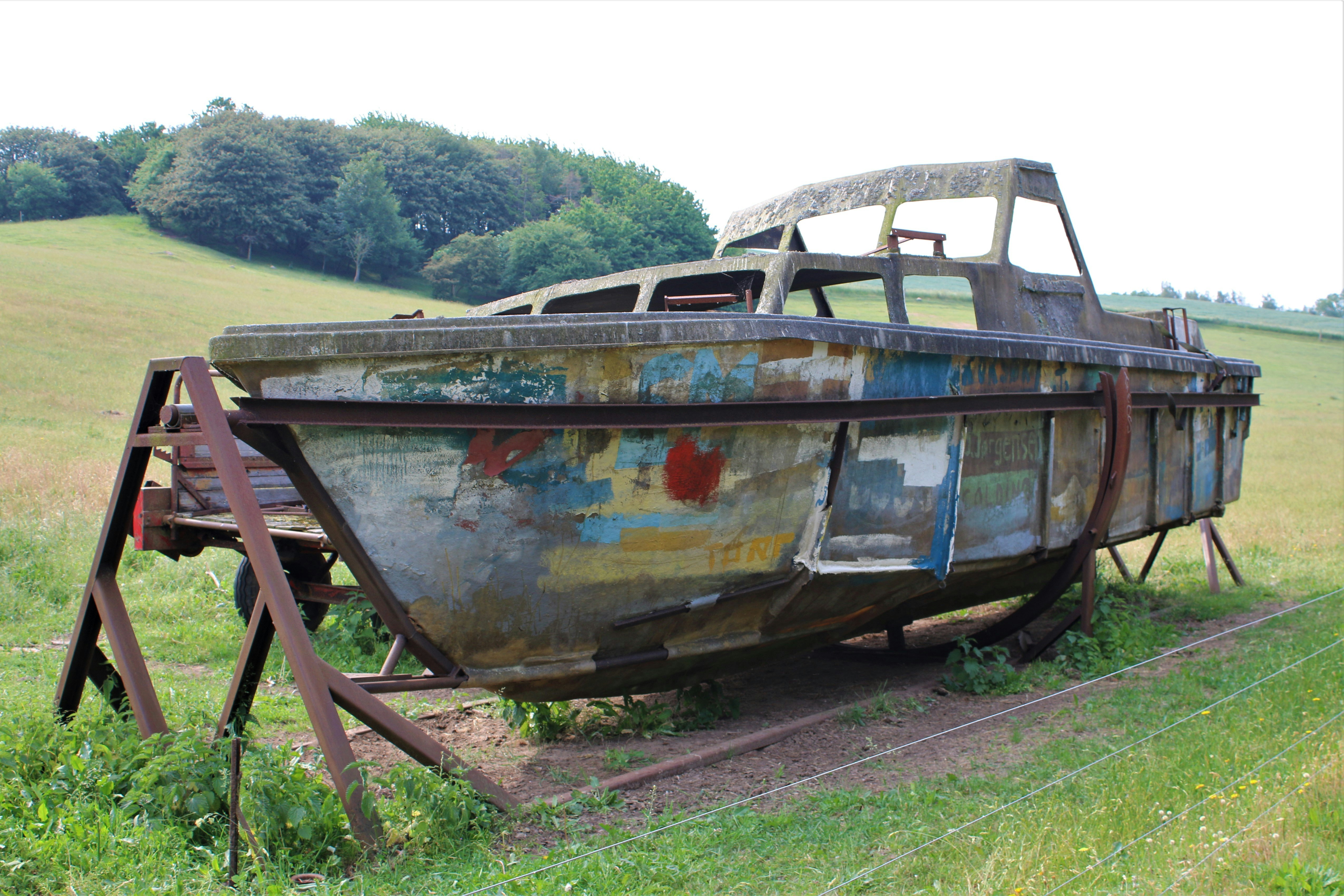un bateau rouillé assis au sommet d’un champ couvert d’herbe