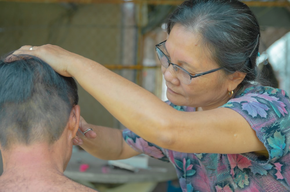 a woman cutting a mans hair with scissors