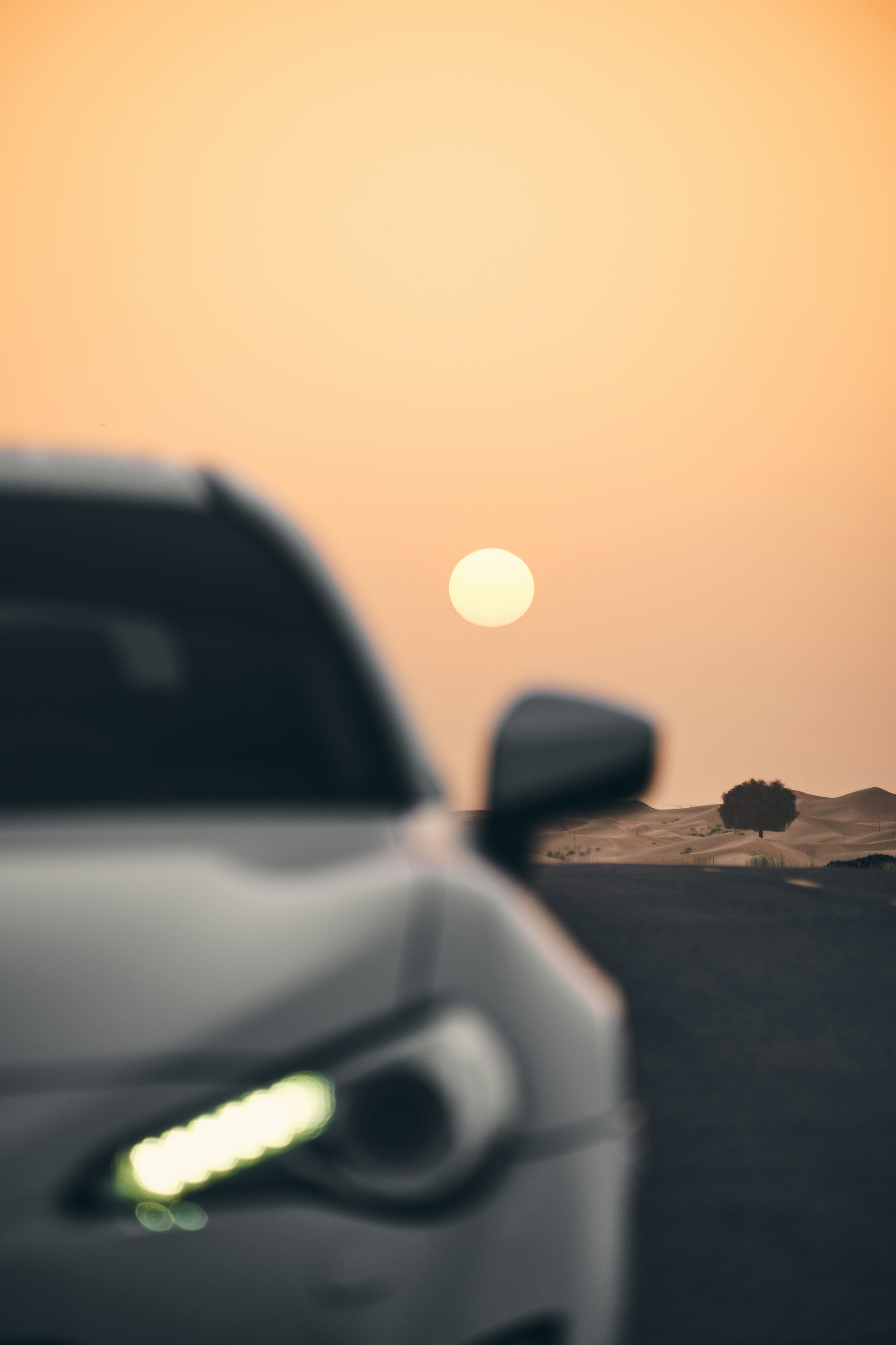 a car driving down a road with a sunset in the background