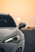 Front view of a compact car with headlights on during sunset