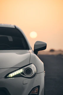 Front view of a compact car with headlights on during sunset
