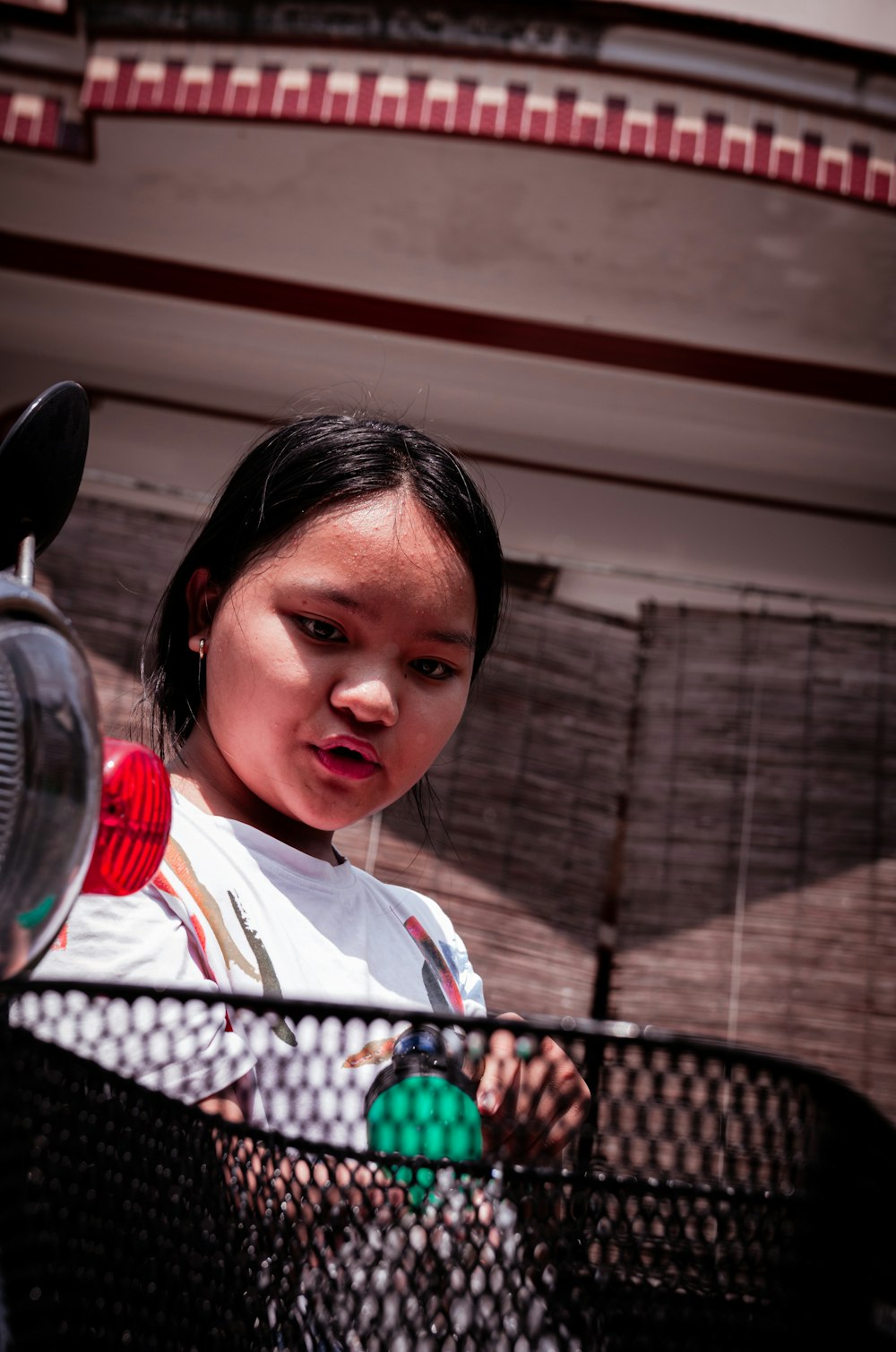 a young girl standing behind a fence holding a frisbee