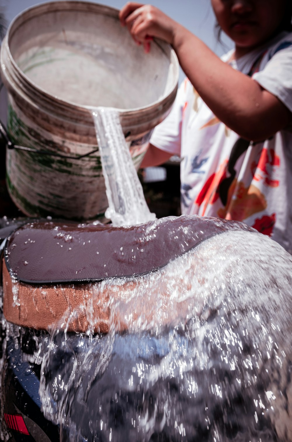 a person pouring water from a bucket into a bowl