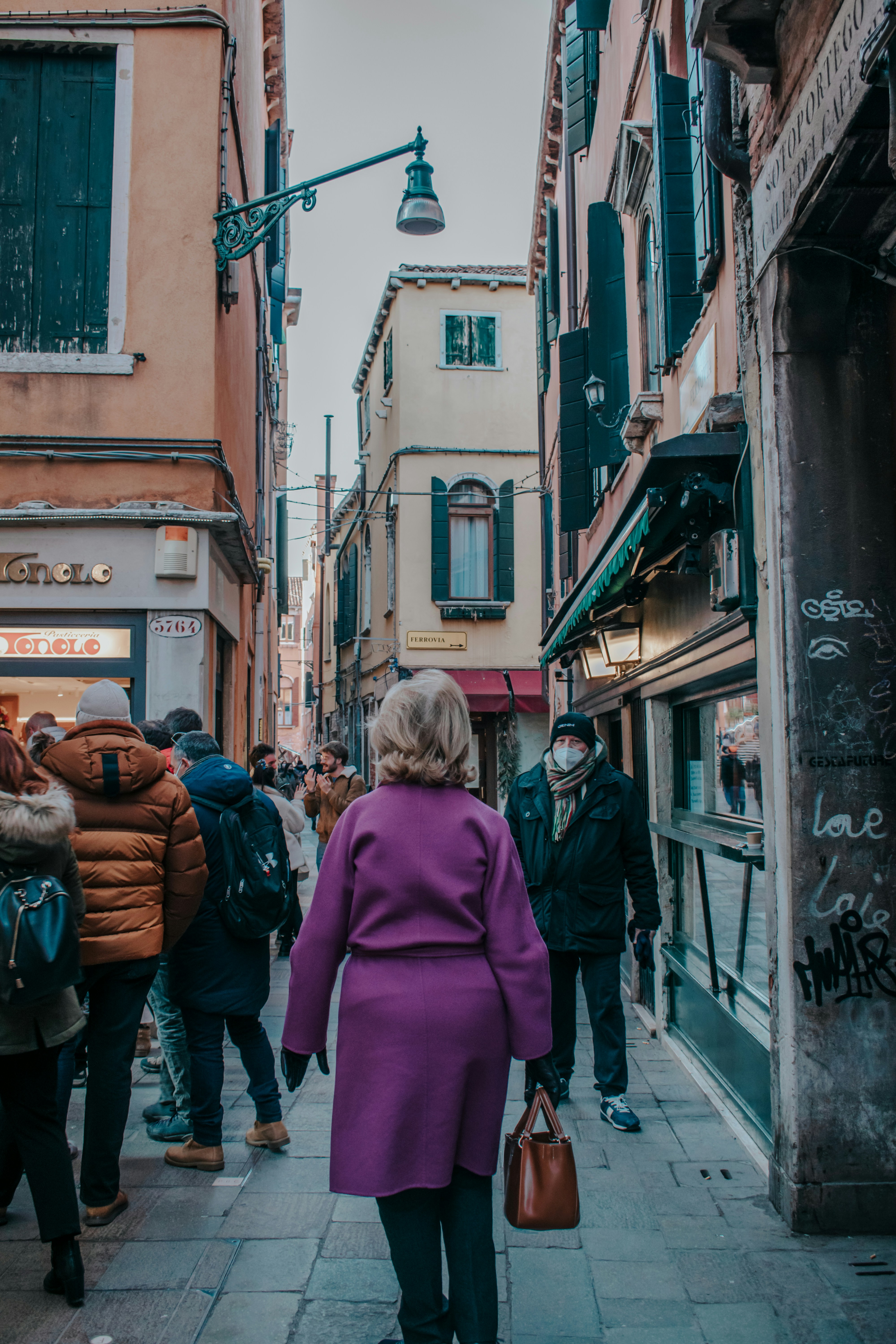 a woman in a purple coat walking down a street