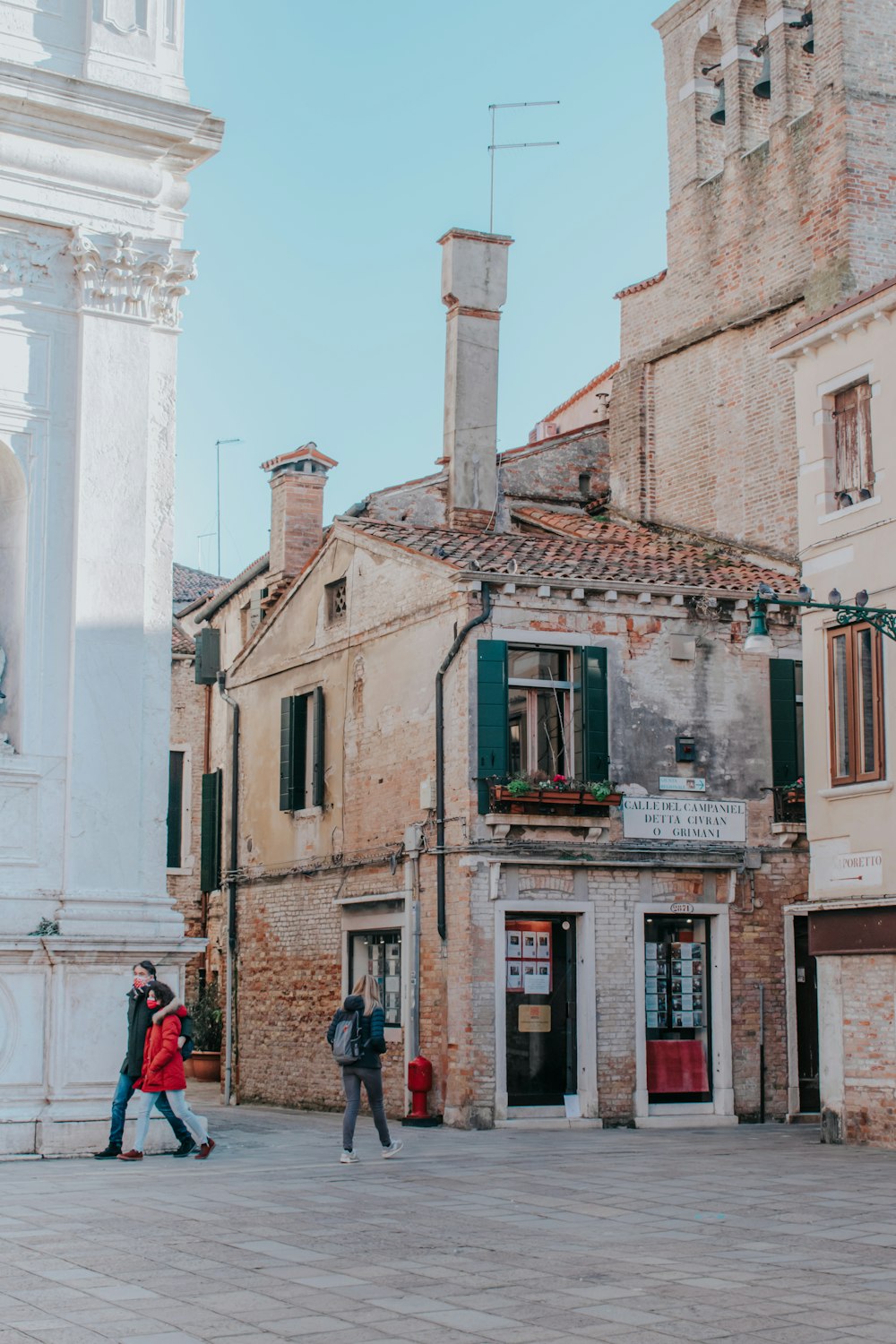 a couple of people walking down a street next to tall buildings