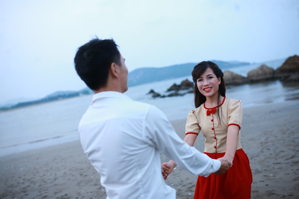 a man and a woman holding hands on a beach