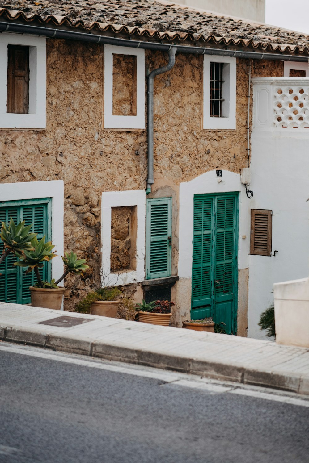 a white building with green shutters and a potted plant