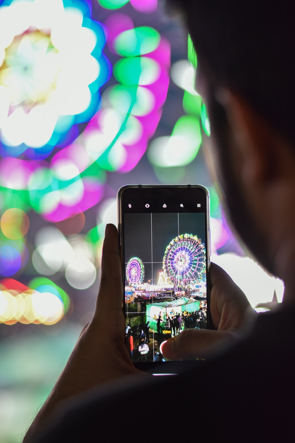 a man taking a picture of a carnival with his cell phone