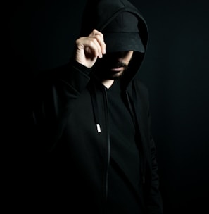 a man in a black hoodie standing in the dark