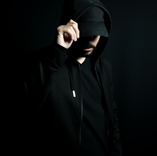 a man in a black hoodie standing in the dark