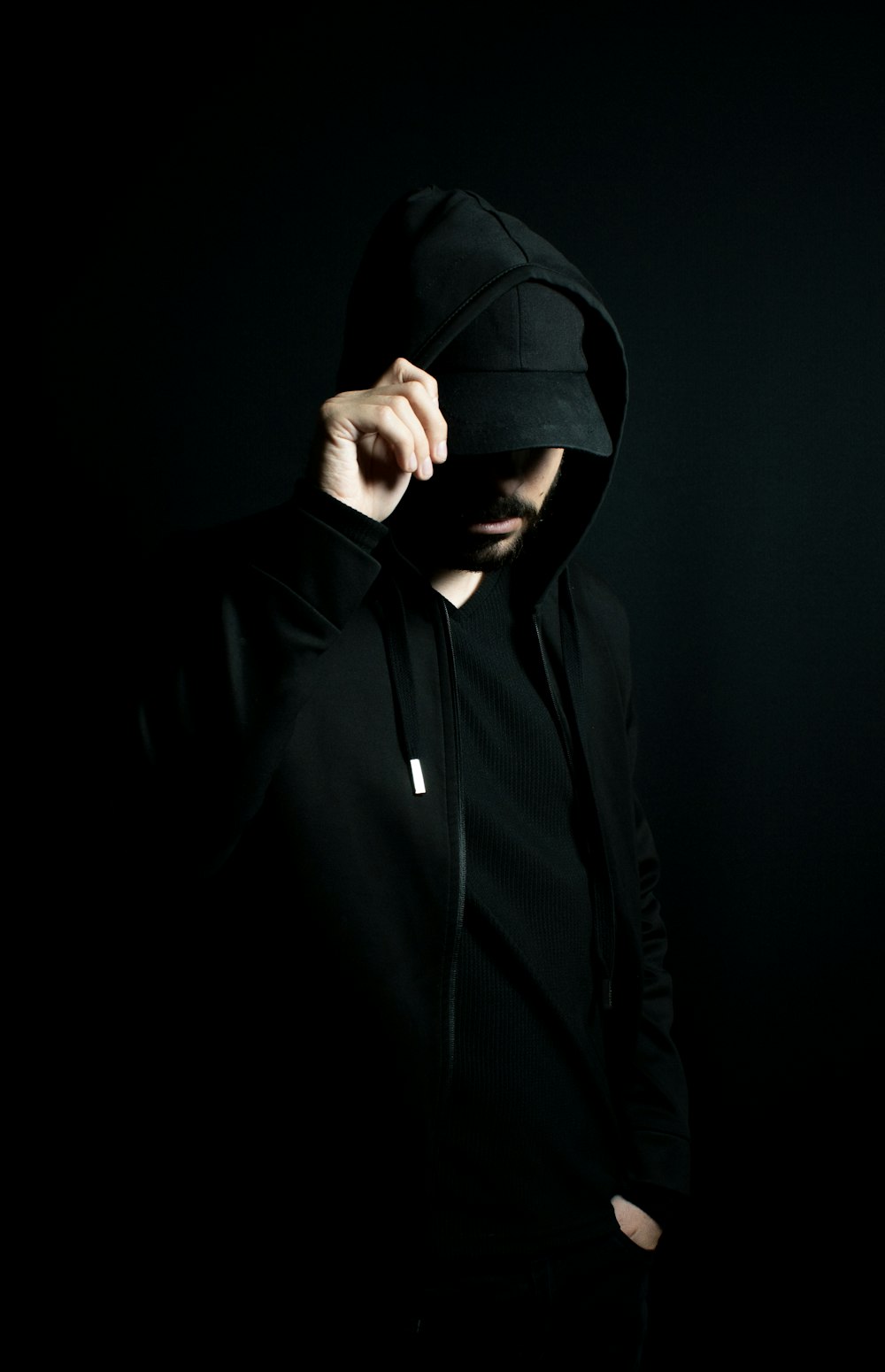 a man in a black hoodie standing in the dark