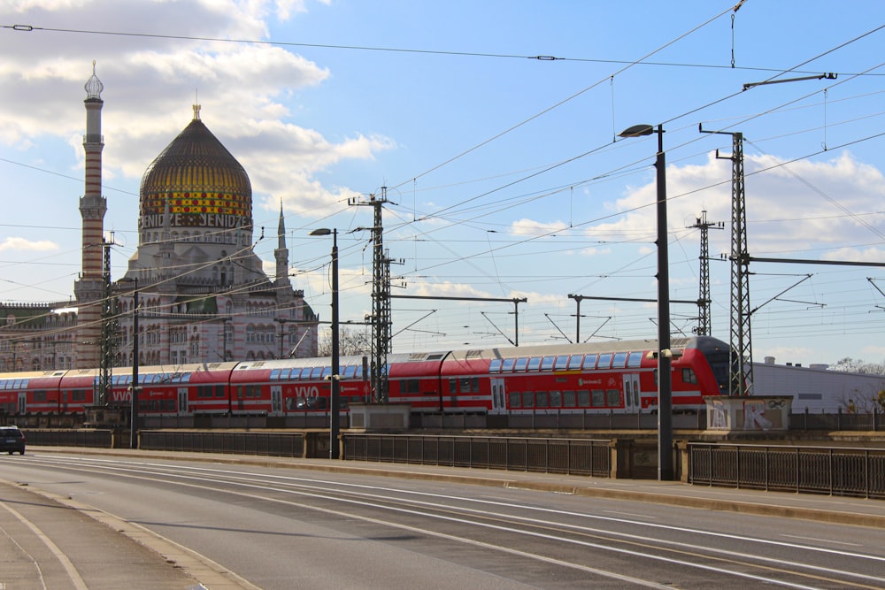 a red train traveling down train tracks next to a tall building