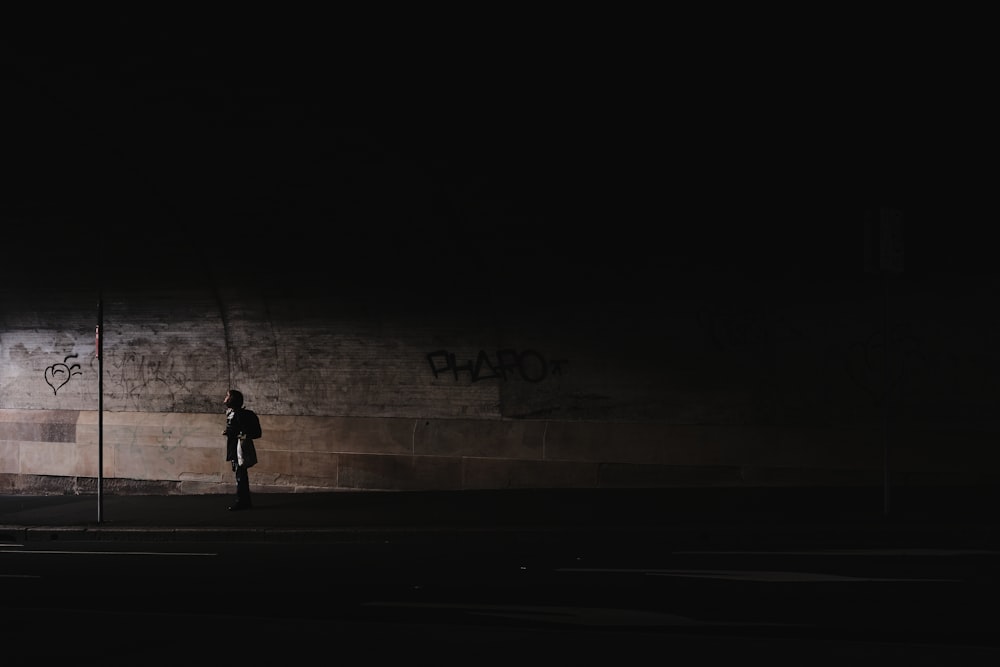 a person standing in the dark near a wall