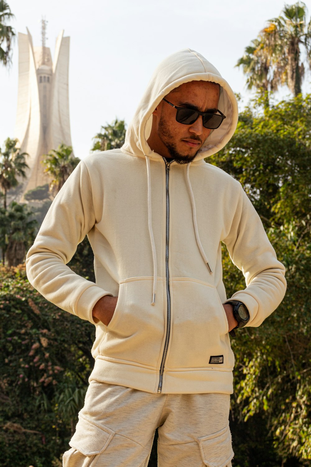 a man in a white hoodie is standing with his hands on his hips