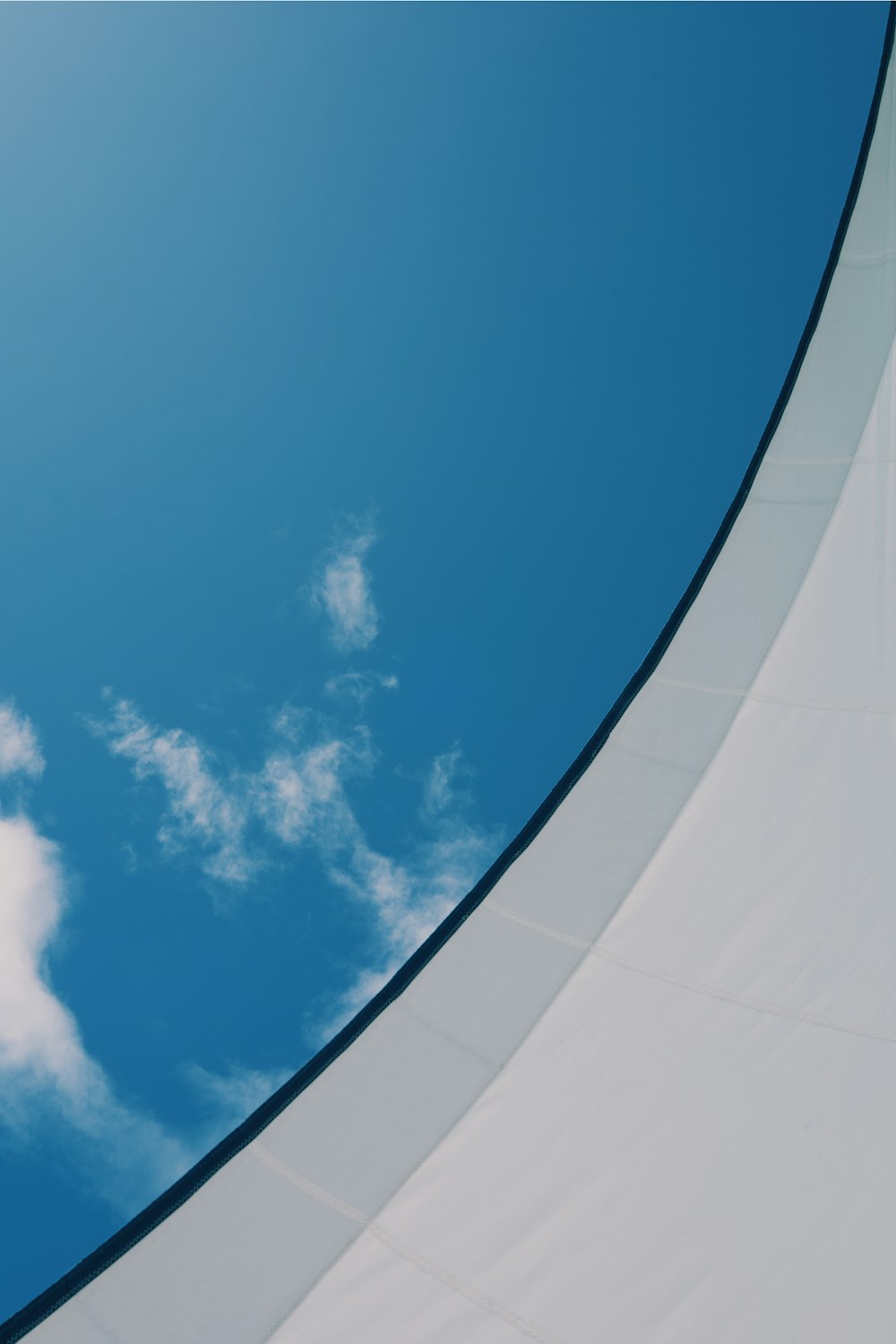 um avião voando através de um céu azul com nuvens brancas