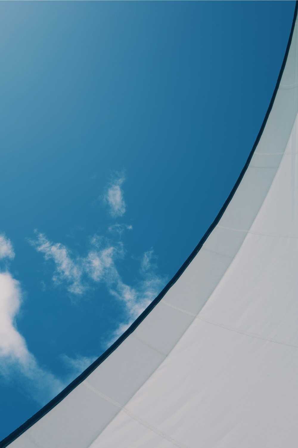 a plane flying through a blue sky with white clouds