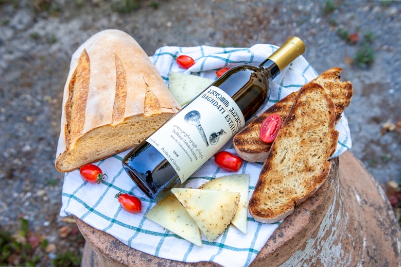 Bread, cheese, and white wine placed on a checkered tablecloth