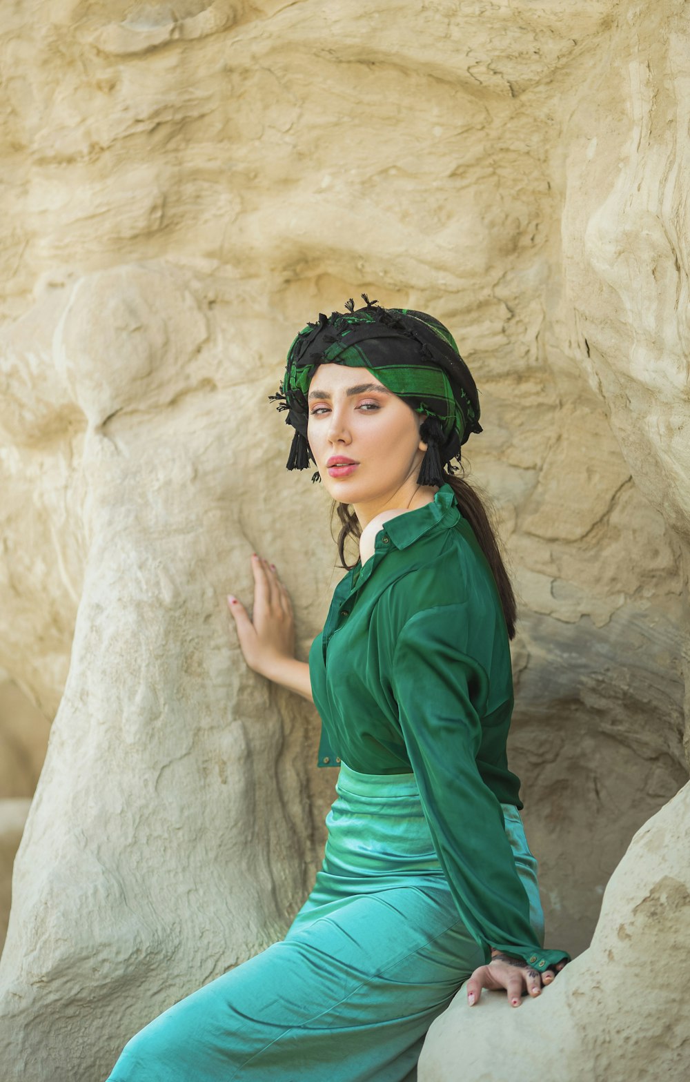 a woman in a green dress sitting on a rock