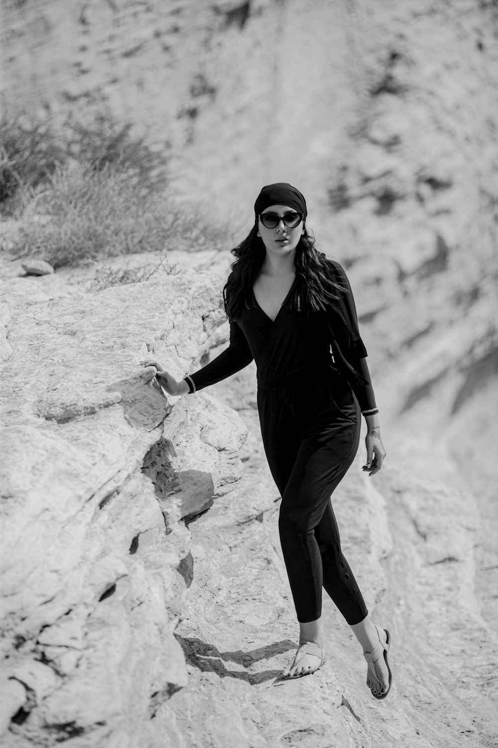 a woman in a black jumpsuit is walking on a rock