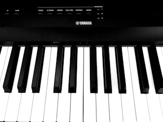 A close-up view of a keyboard focusing on the black and white keys. The name Yamaha is visible, indicating the brand of the instrument. There are control buttons above the keys for different instrument sounds.