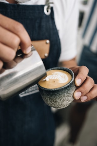 Barista carefully pouring milk into espresso to create a perfect cappuccino foam heart