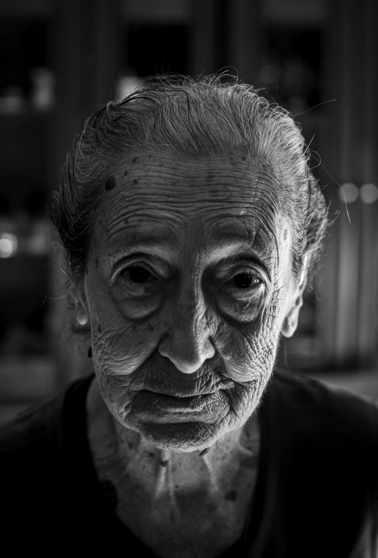 An elderly sitter lit from one side, every line in the face held sharp