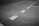 A section of asphalt road is visible with marked white dashed lines indicating separation lanes. The surface has a coarse texture and appears slightly worn.